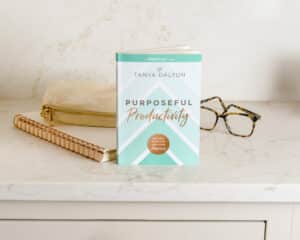 A book on productivity for women next to a pair of glasses